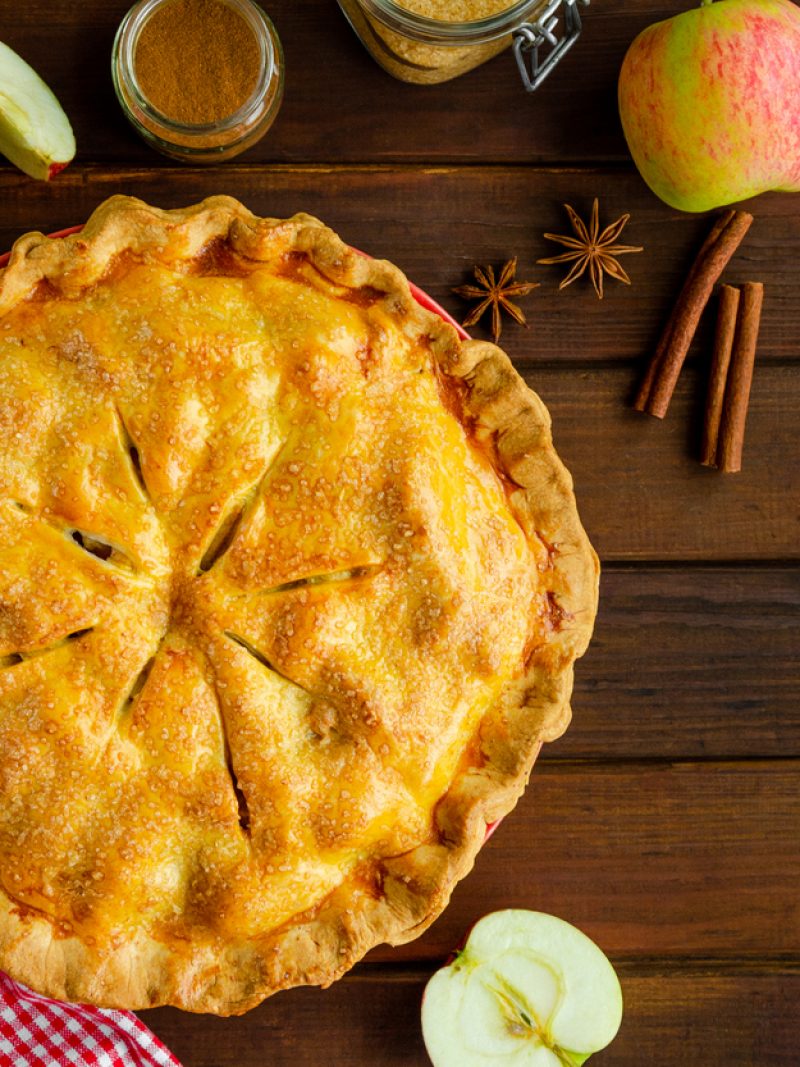 Classic American apple pie with cinnamon on a dark wooden background. Rustic style. Top view, copy space